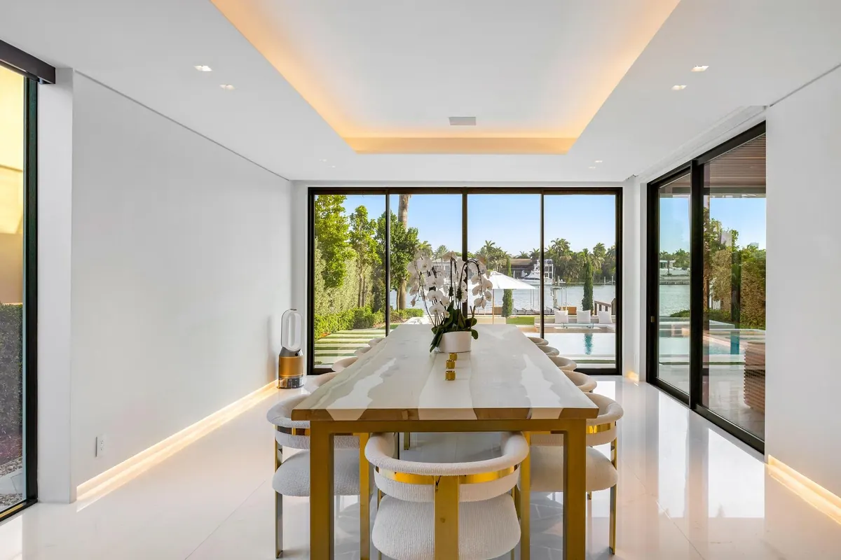 Light-filled dining room with full-height windows and a pale stone table