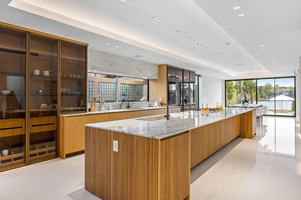 Open kitchen with a pale stone island and dark cabinetry