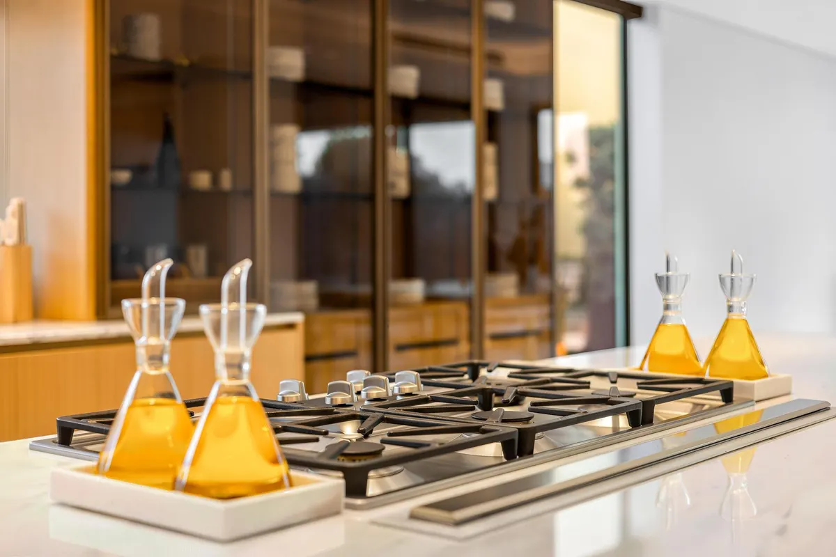 Gas cooktop with glass oil dispensers on a kitchen island