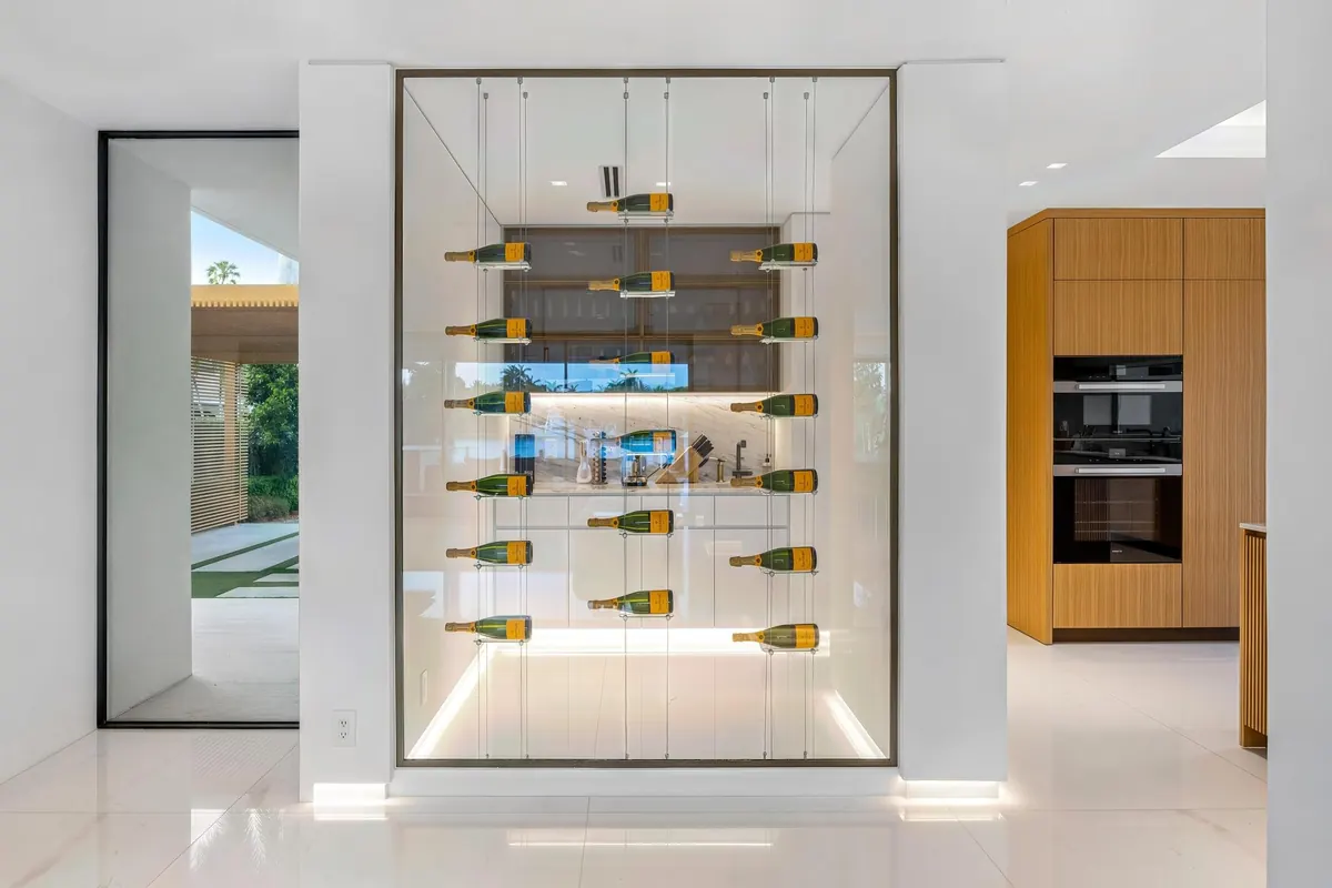Wall-mounted wine display between a white hallway and kitchen