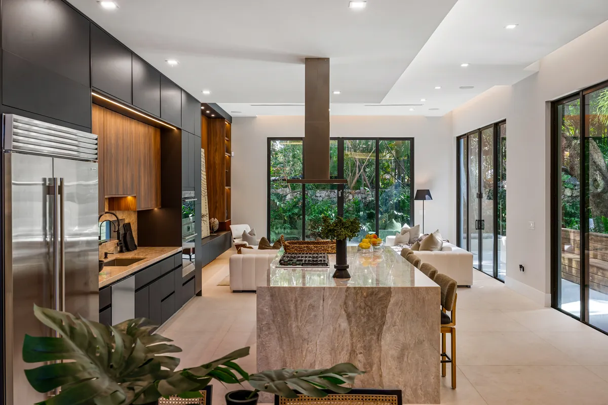 Kitchen with a stone island, tall wood cabinetry and windows facing greenery