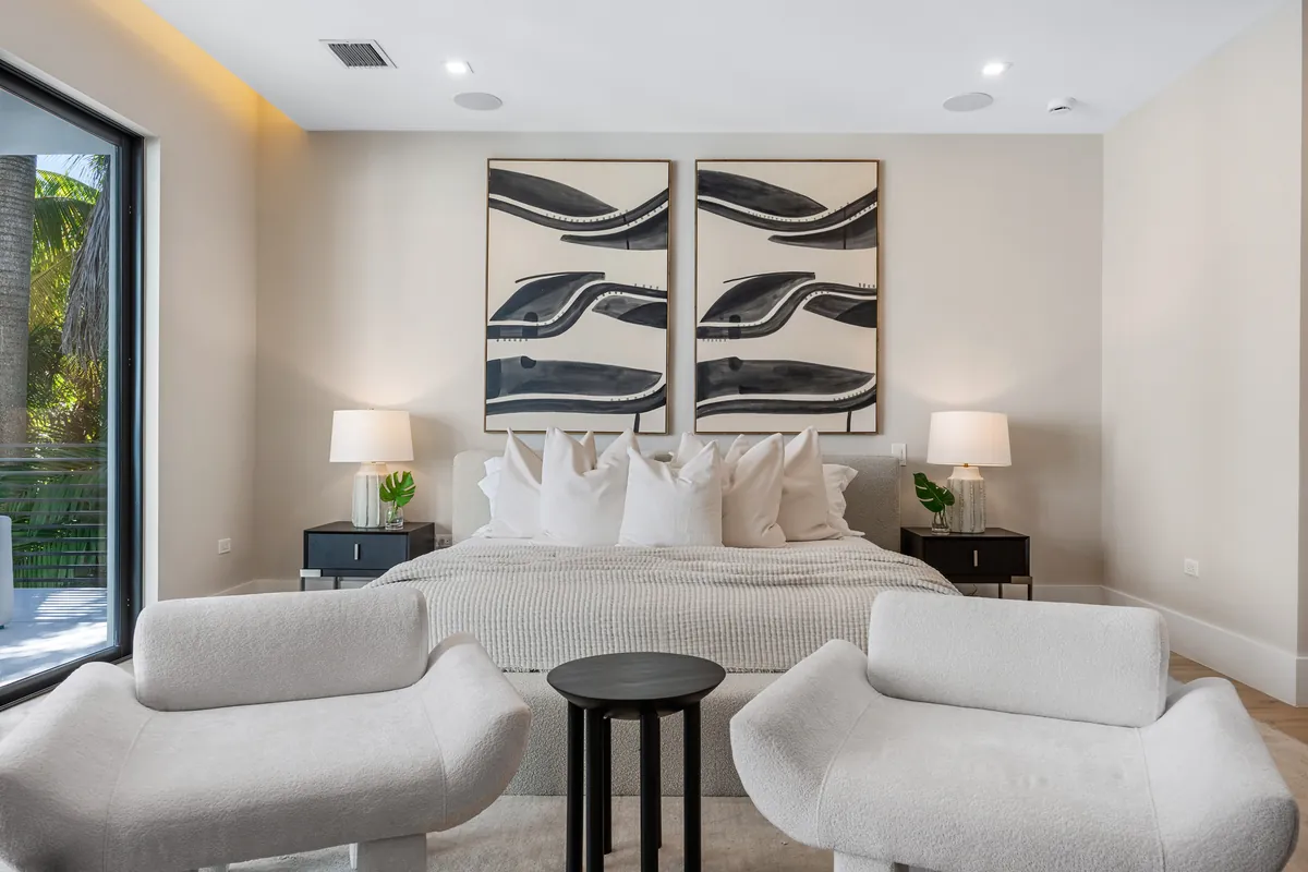 Bedroom with pale upholstered furniture, abstract artwork and a garden window