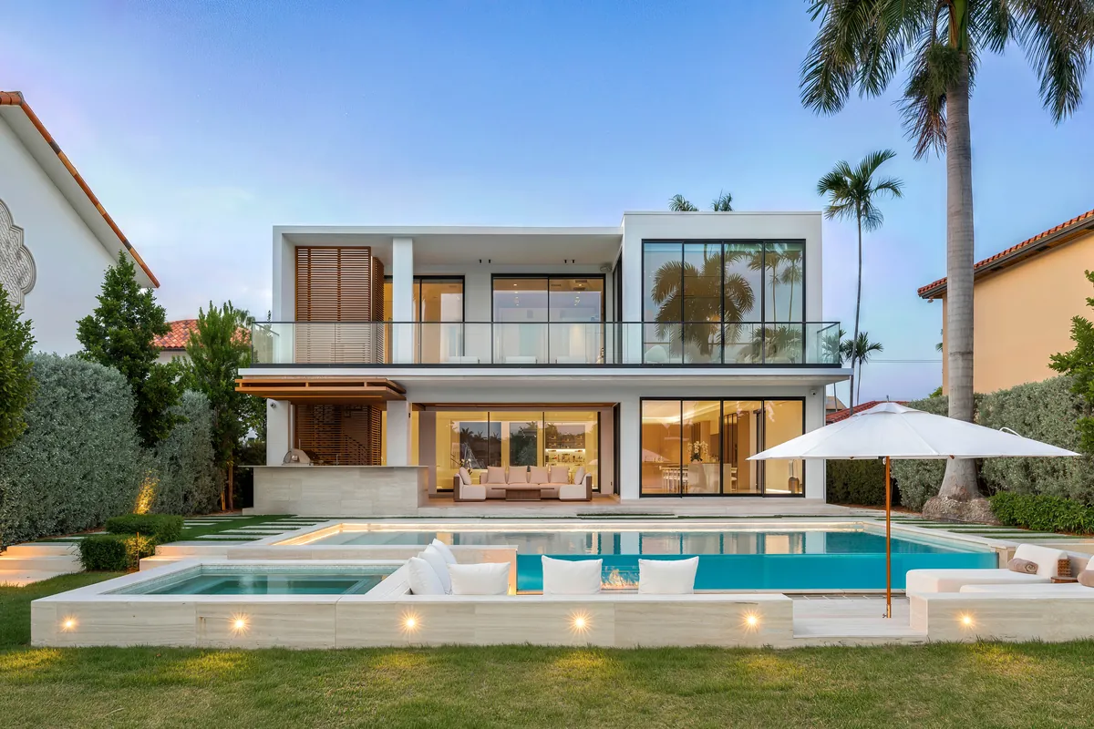Two-story home with glass doors, a swimming pool and palms