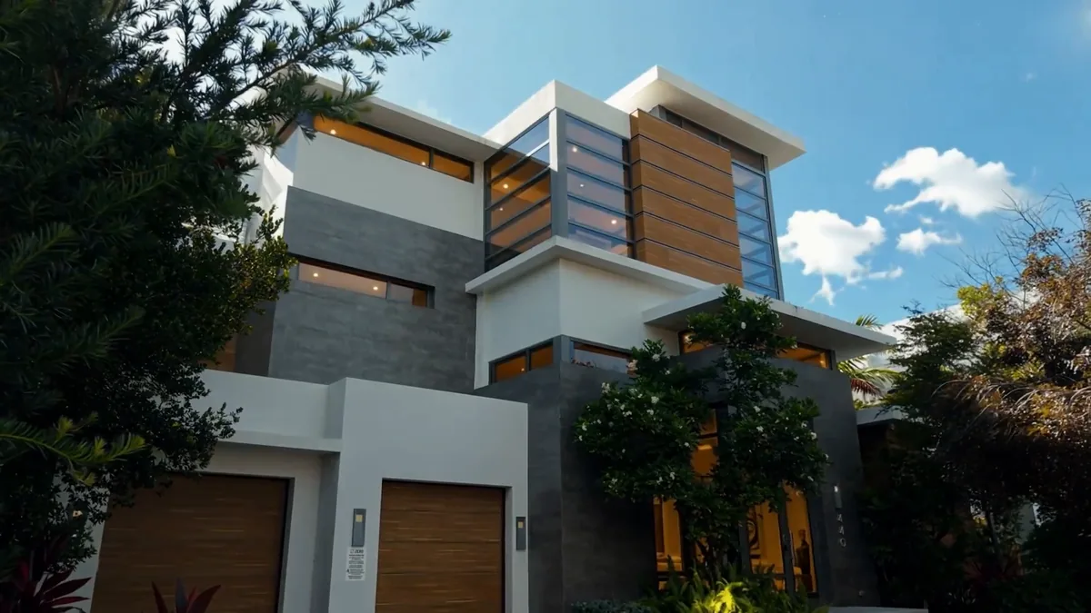 Frame from the 440 Mola Avenue property film: modern home with glass, wood panels and a white facade