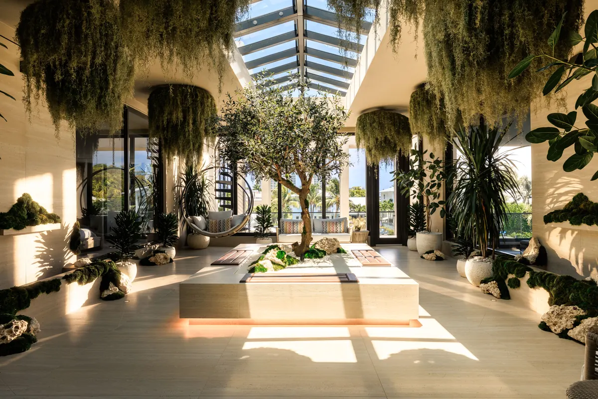 Sunlit atrium with a glass roof, hanging greenery and a central planter