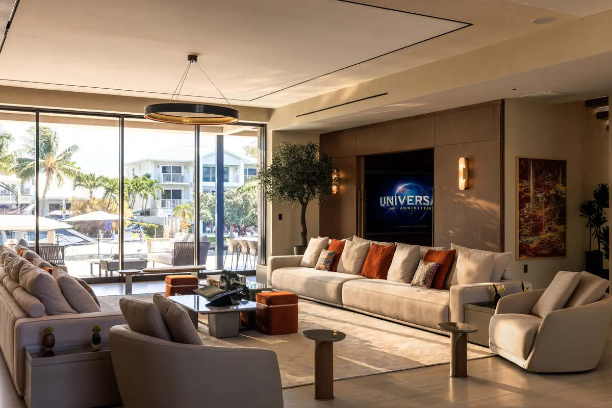 Living room with pale sofas and open glass doors overlooking a waterfront terrace
