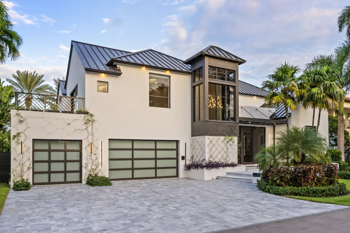 Light stone and white two-story home with dark-framed windows and garage doors