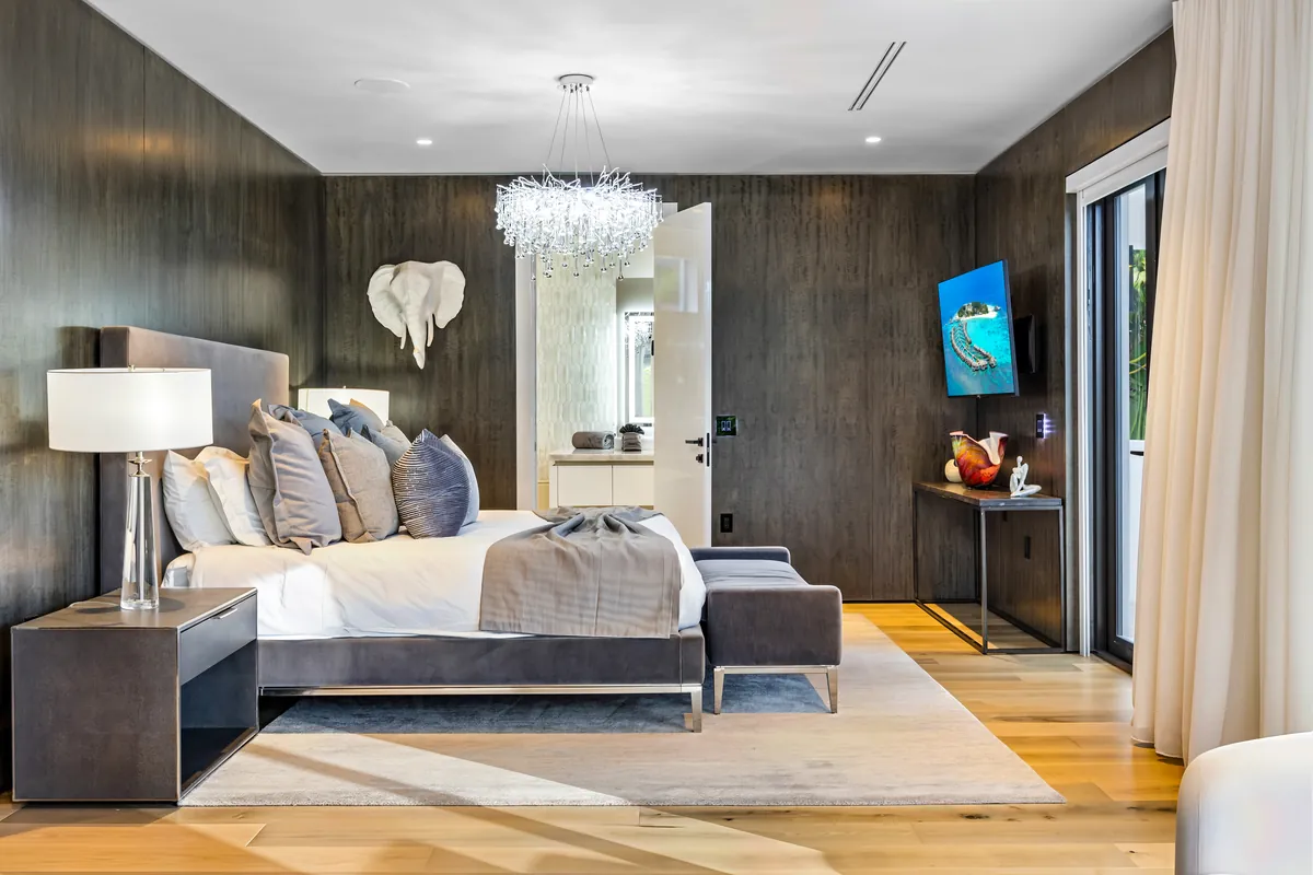 Bedroom with dark wall finishes, a pale upholstered bed and a chandelier
