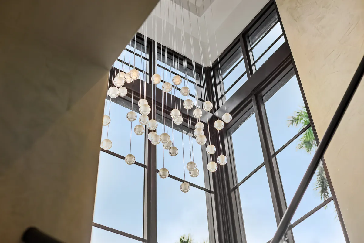 Hanging glass lights suspended beside a staircase and tall corner windows