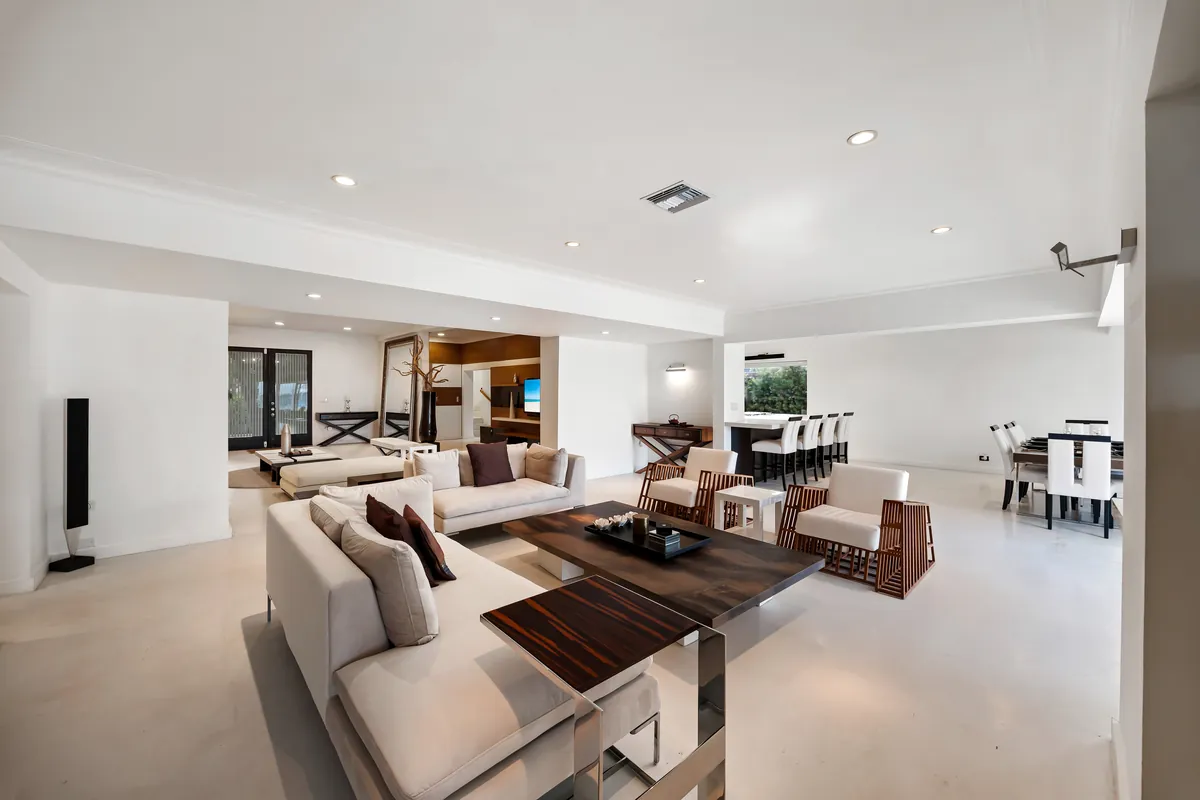 Open living and dining space with pale seating, dark tables and a waterfront outlook