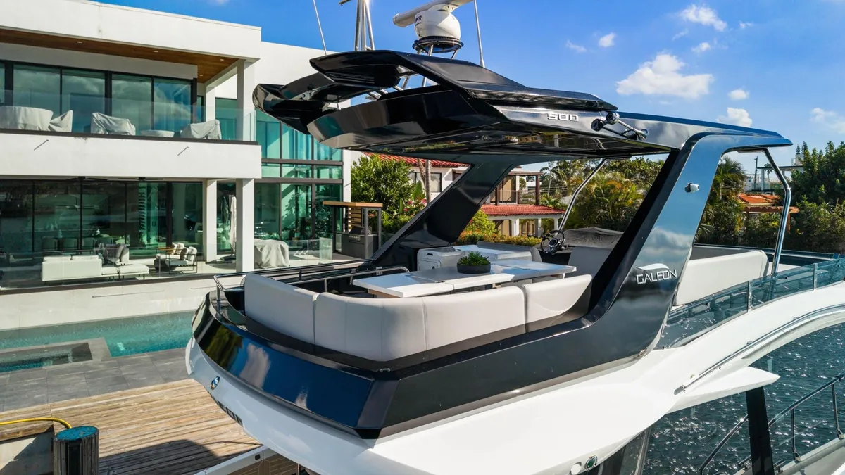 Aft seating and swim platform of a yacht beside a waterfront home