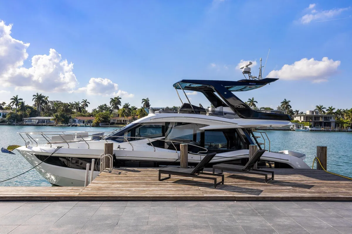 Motor yacht alongside a waterfront dock under a blue sky